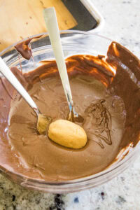 dipping peanut butter footballs in melted chocolate