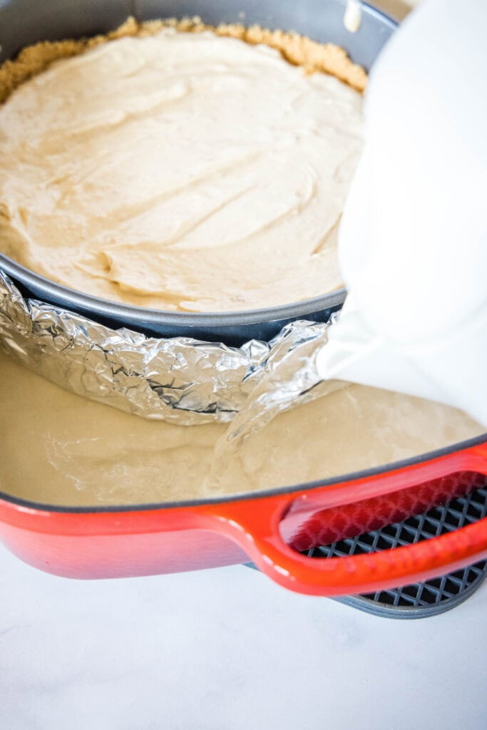pouring water into water bath to bake cheesecake