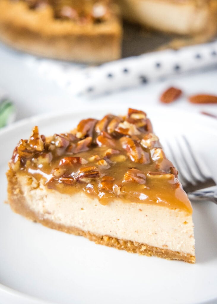 slice of cheesecake with pecan pie topping on it on a white plate