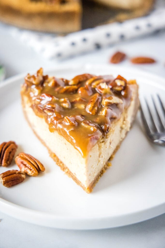 pecan pie cheesecake on a white plate with a fork next to it