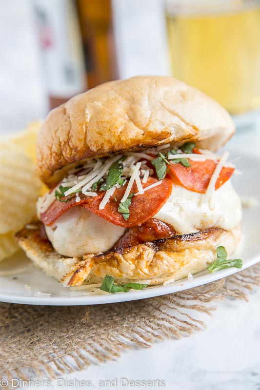 A close up of pepperoni pizza burger on a plate with potato chips