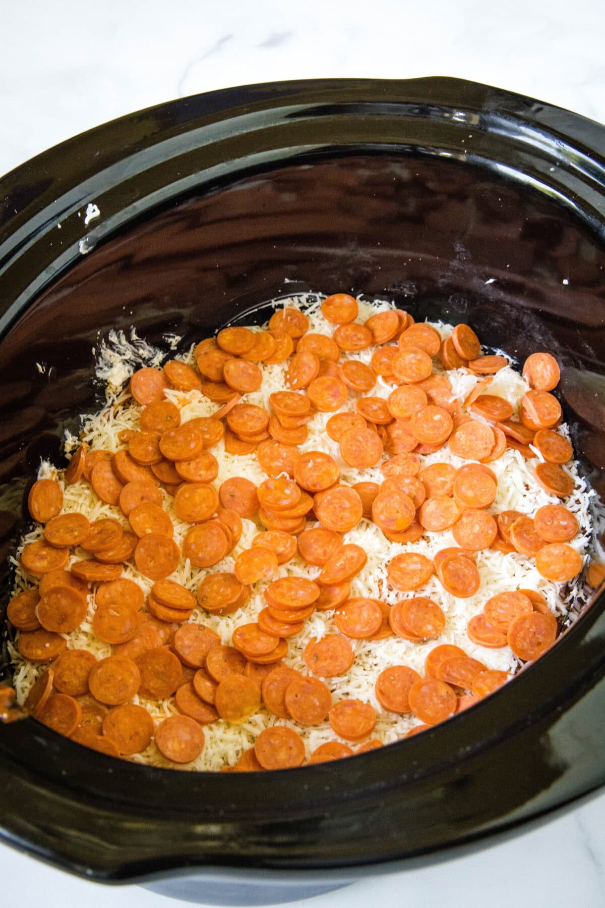 layering pepperoni for pizza dip in crockpot