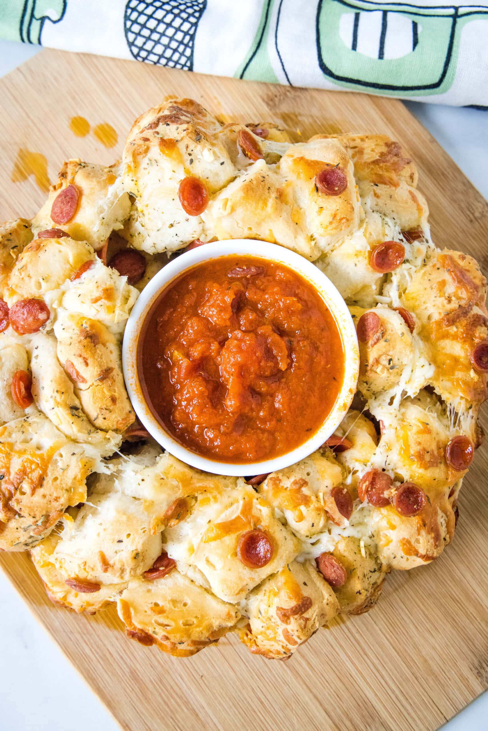 Overhead view of pizza monkey bread with a bowl of pizza sauce in the middle hole.