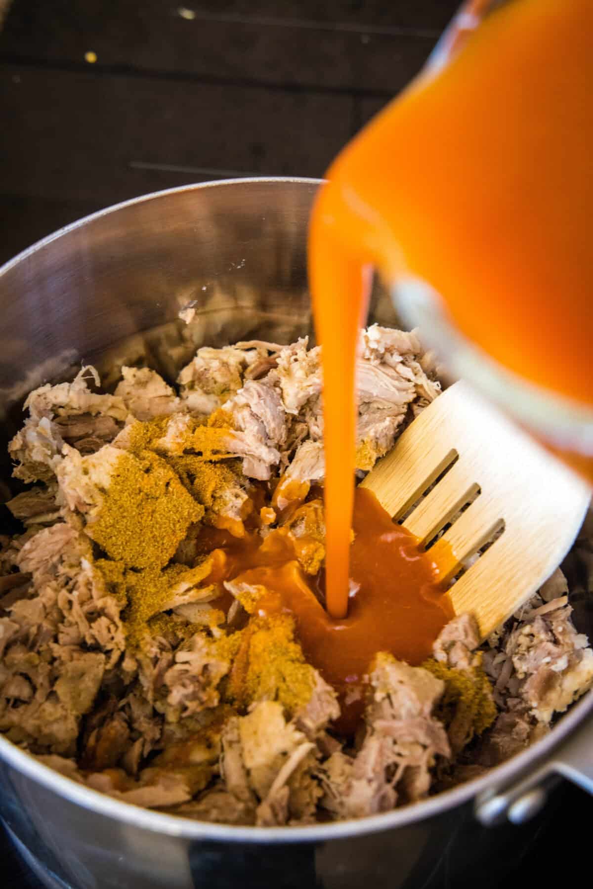 pouring enchilada sauce over pulled pork