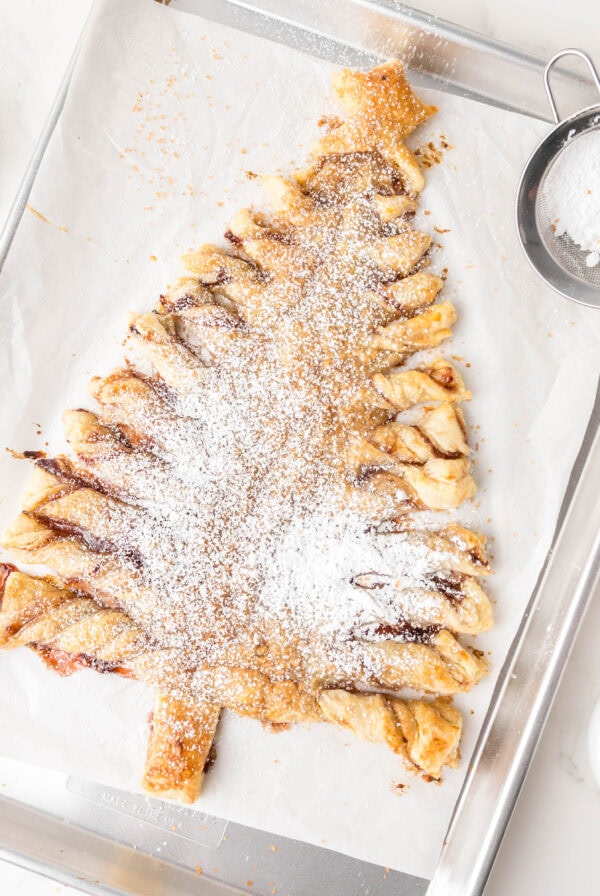 cropped close up puff pastry christmas tree dusted with powdered sugar on a baking sheet