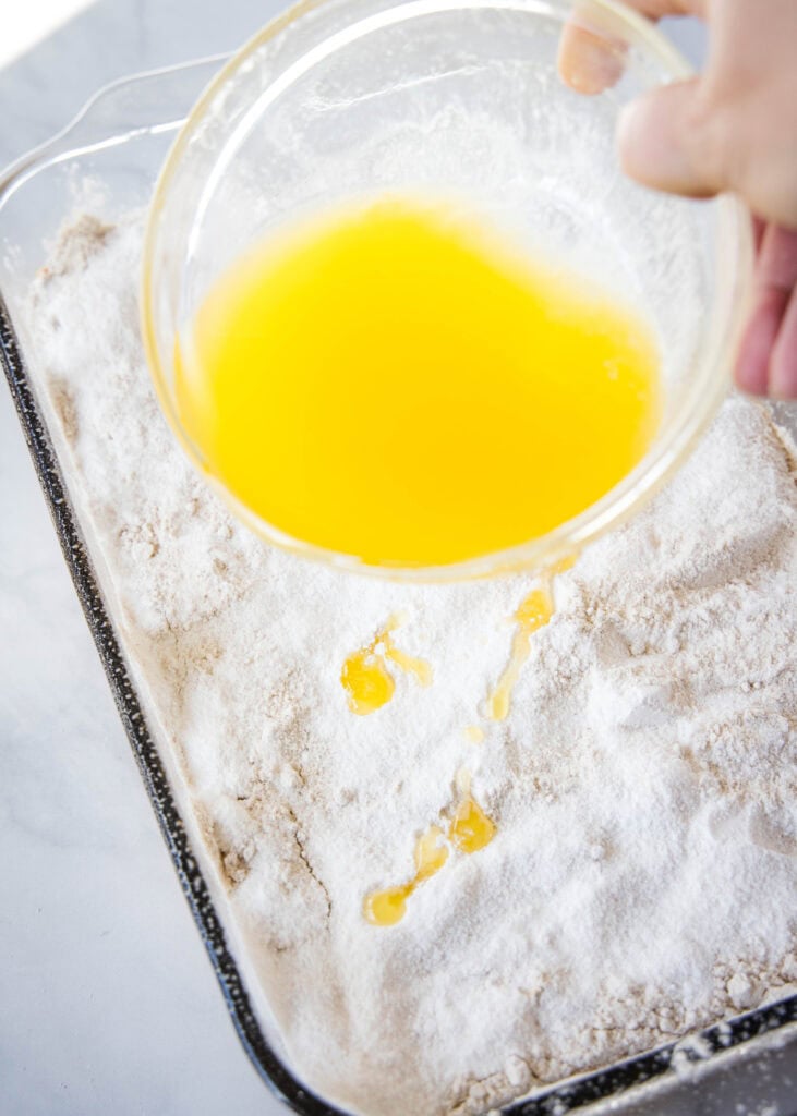 pouring melted butter over dump cake
