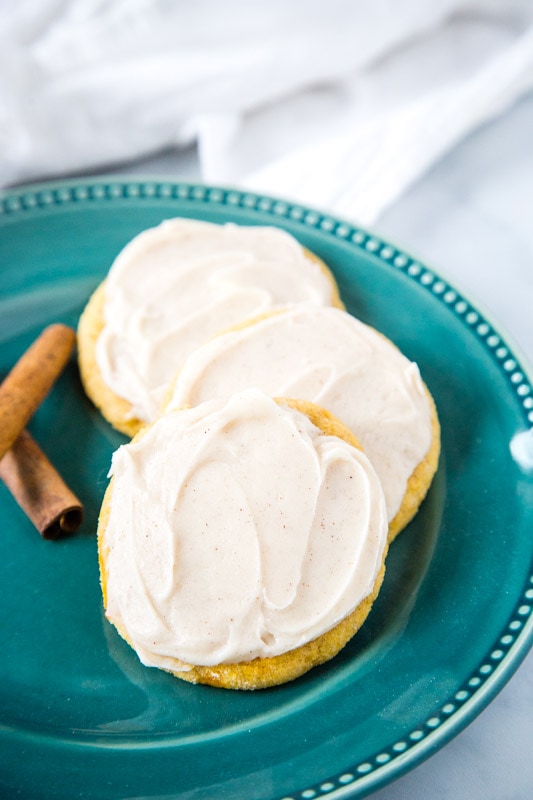 frosted pumpkin cookies on teal plate