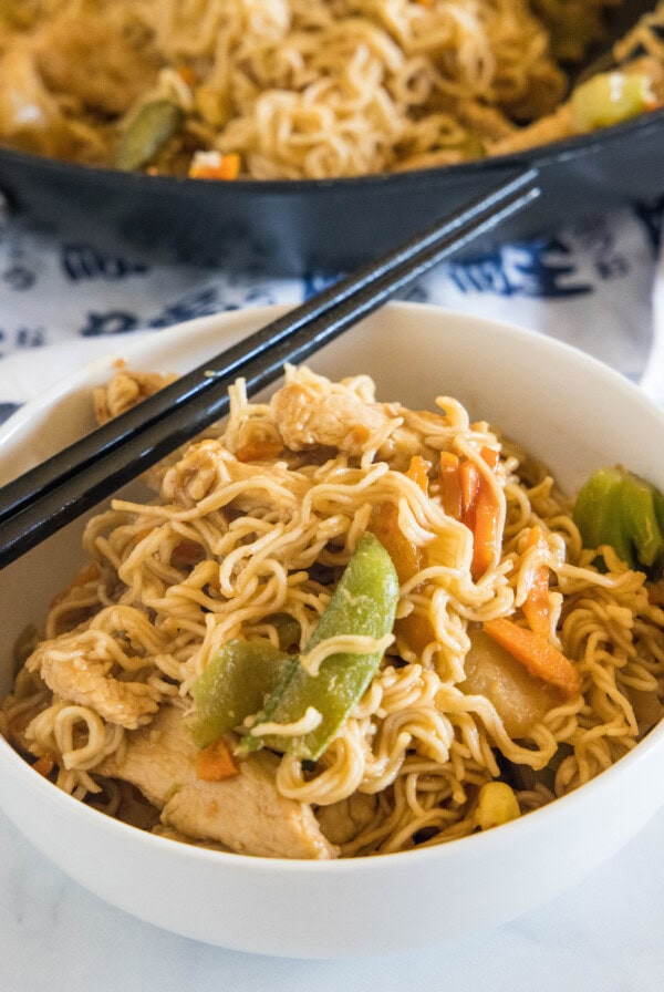 Ramen stir fry in a white bowl with a set of chopsticks resting on the rim of the bowl.
