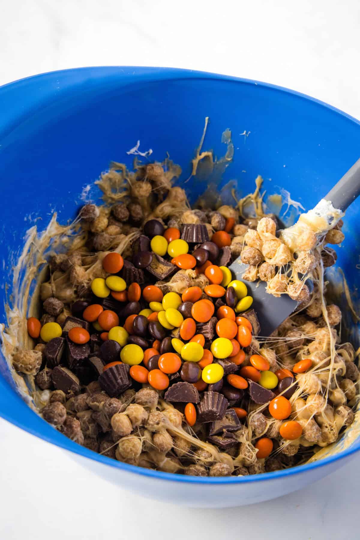 adding reese's pieces and peanut butter cups to a bowl