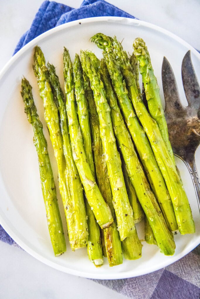 looking down on a plate of asparagus with a serving fork