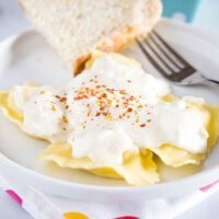 cropped picture of ravioli with white sauce on a plate