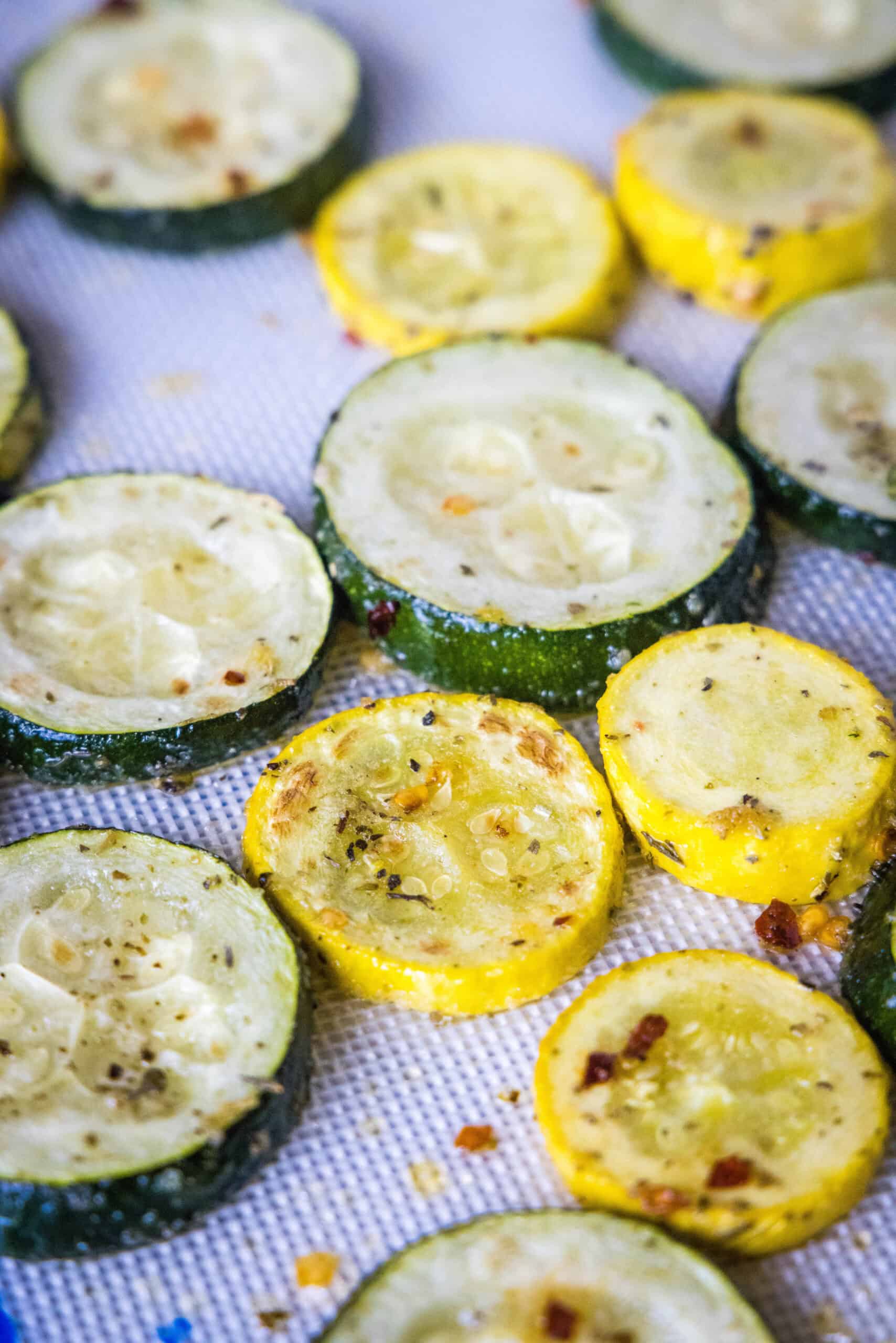 Roasted zucchini and squash slices on a lined baking sheet.