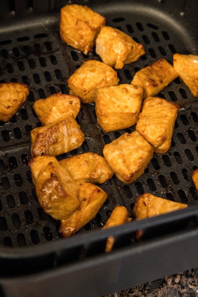 Cooked salmon bites inside the air fryer basket.