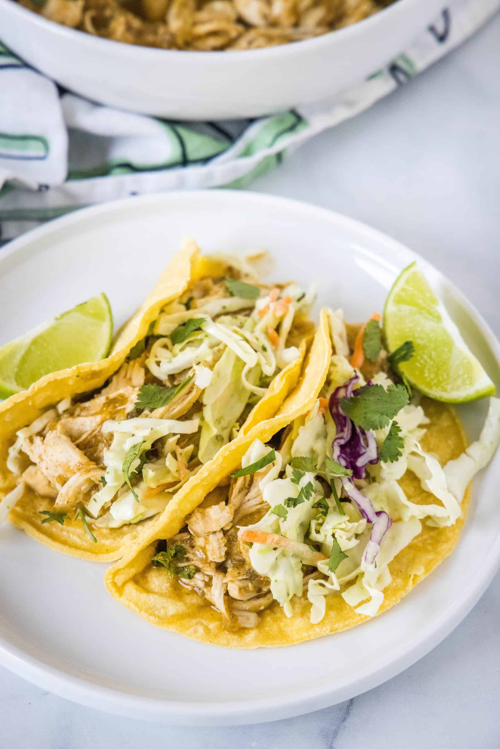 Overhead view of two salsa verde chicken tacos on a white plate.