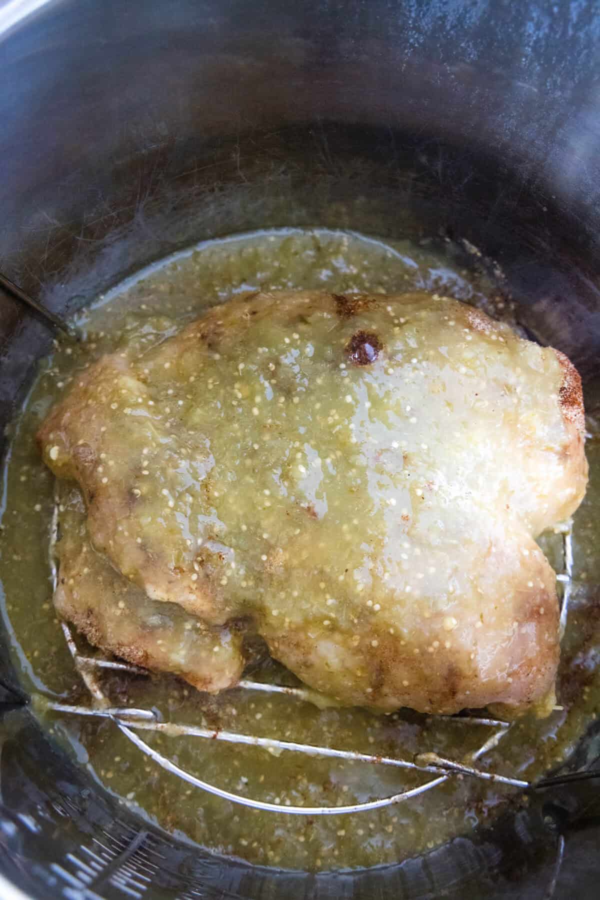 Salsa verde and chicken breasts combined inside the Instant Pot.
