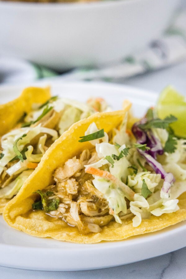 Two salsa verde chicken tacos on a white plate.