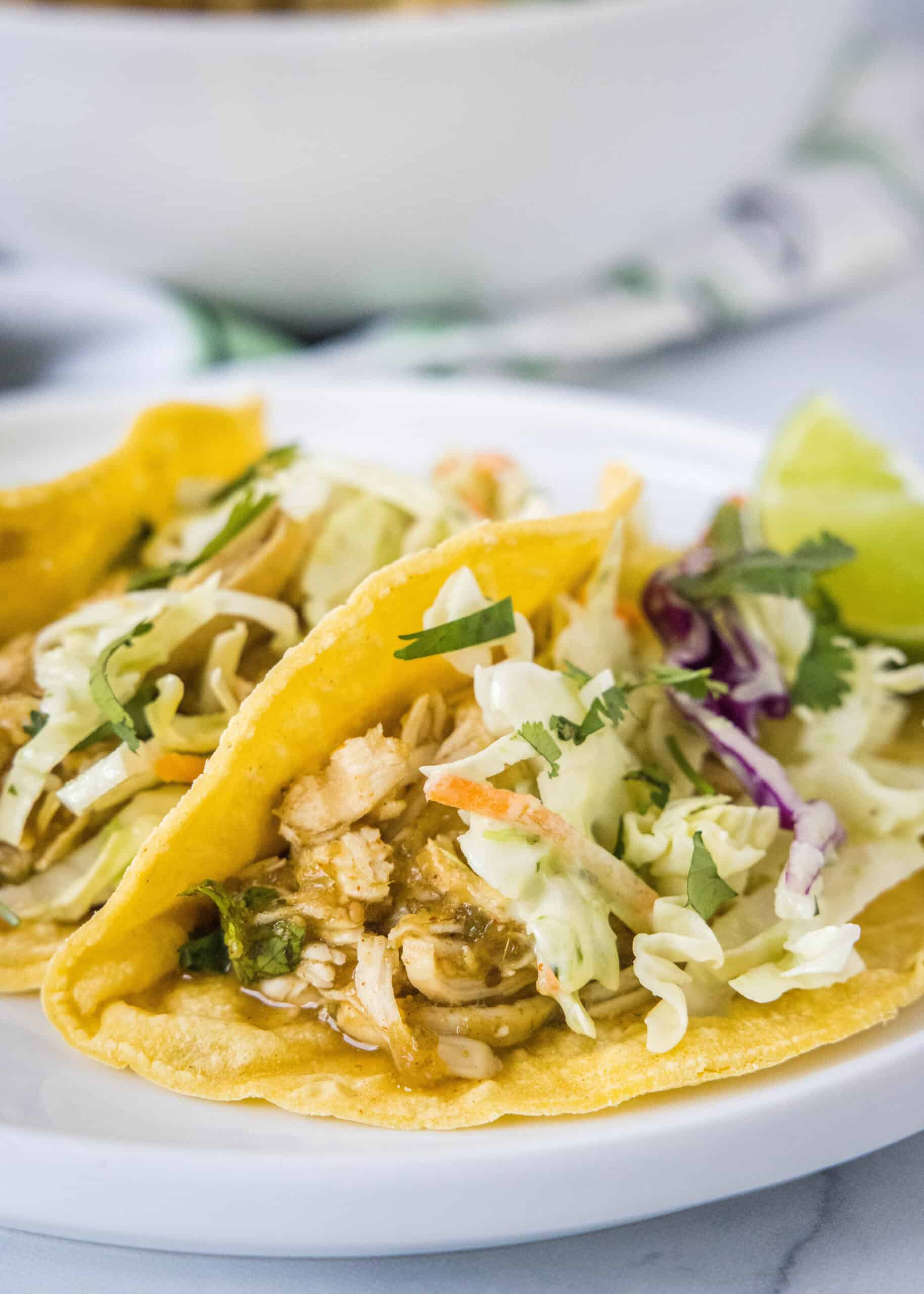 Two salsa verde chicken tacos on a white plate.