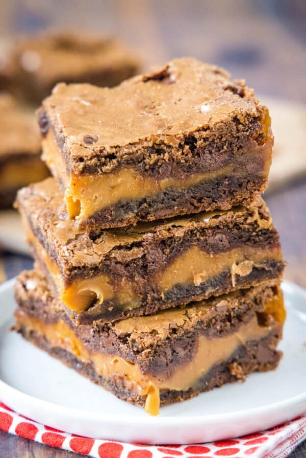 Three salted caramel brownies stacked on a white plate.