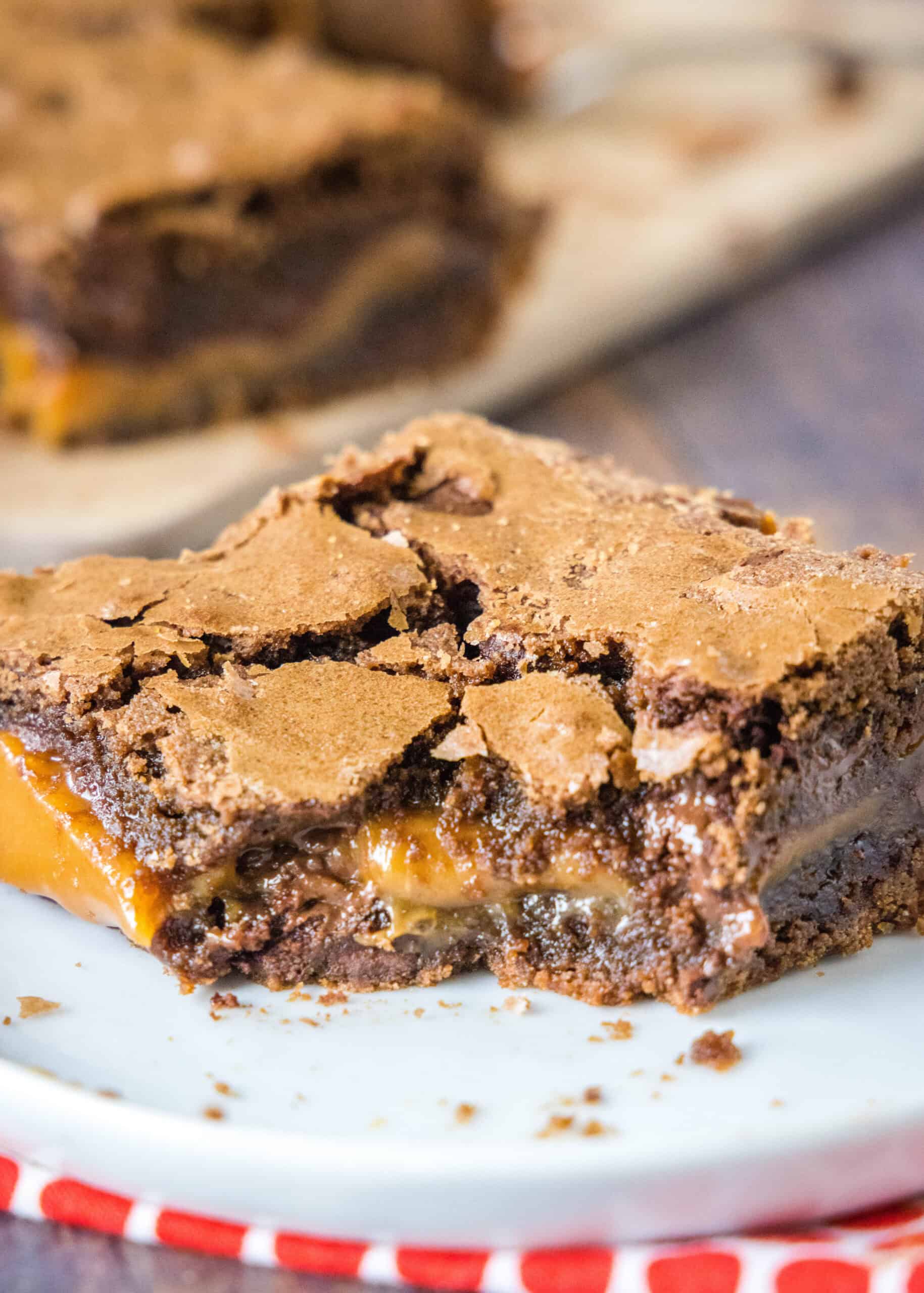Close up of a salted caramel brownie with a bite missing on a white plate.