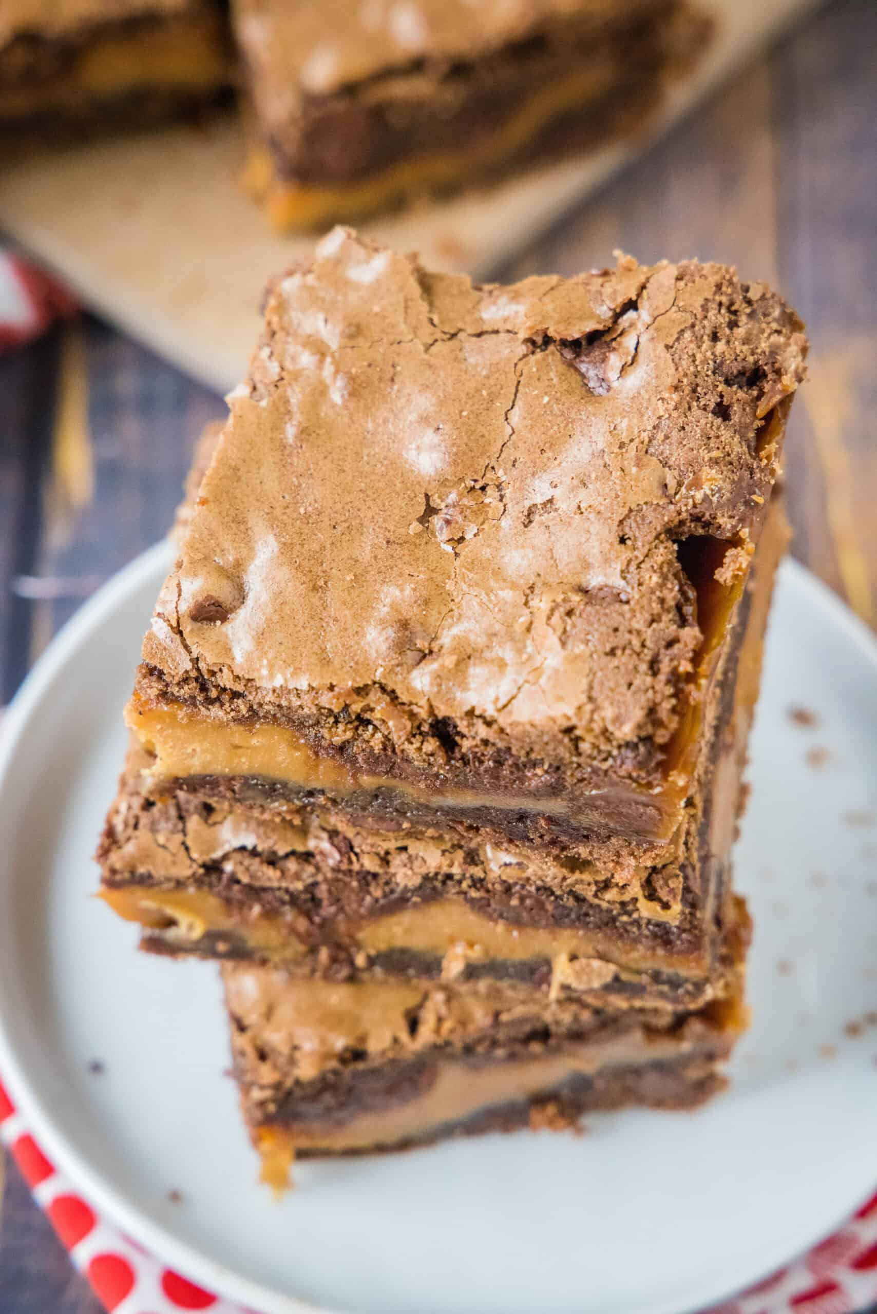 Overhead view of three salted caramel brownies stacked on a white plate.