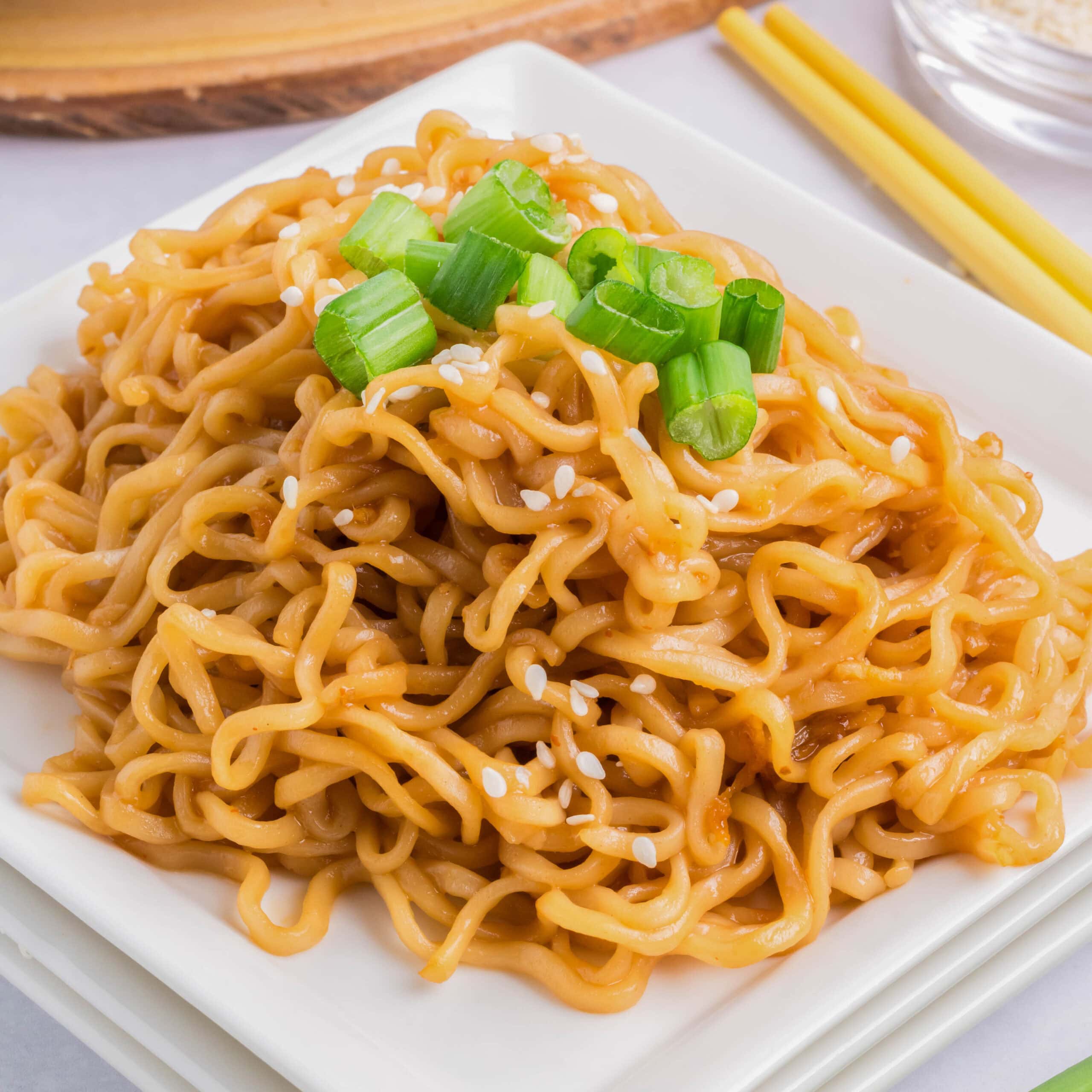 cropped close up sesame noodles on a plate with green onions