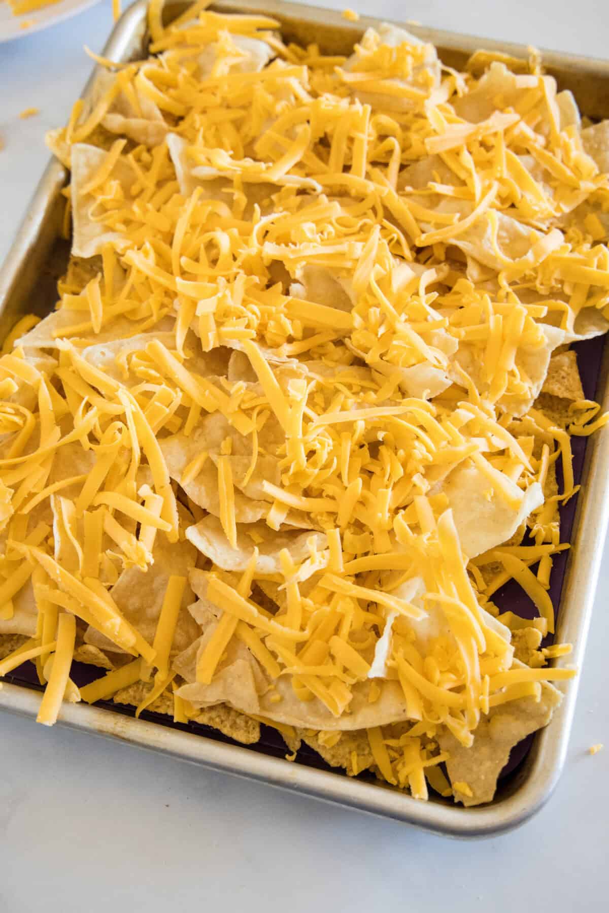 Assembled shrimp nachos topped with shredded cheese.