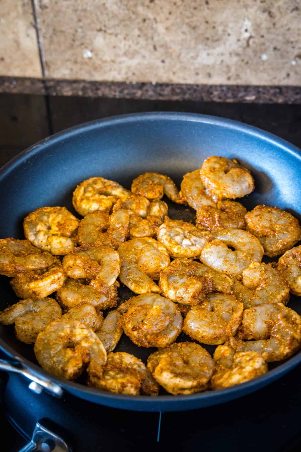 Seasoned shrimp cooking in a skillet.