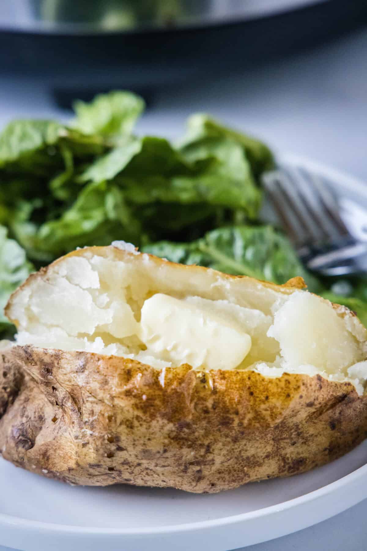 cut open baked potato with butter