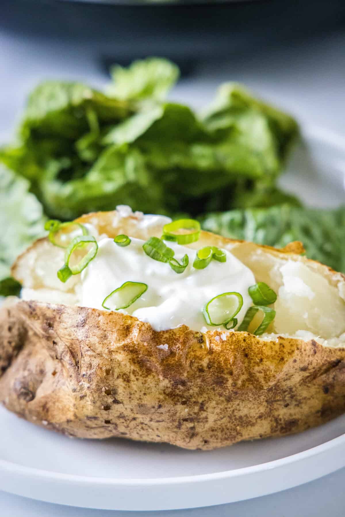 baked potato on a plate with sour cream and chives