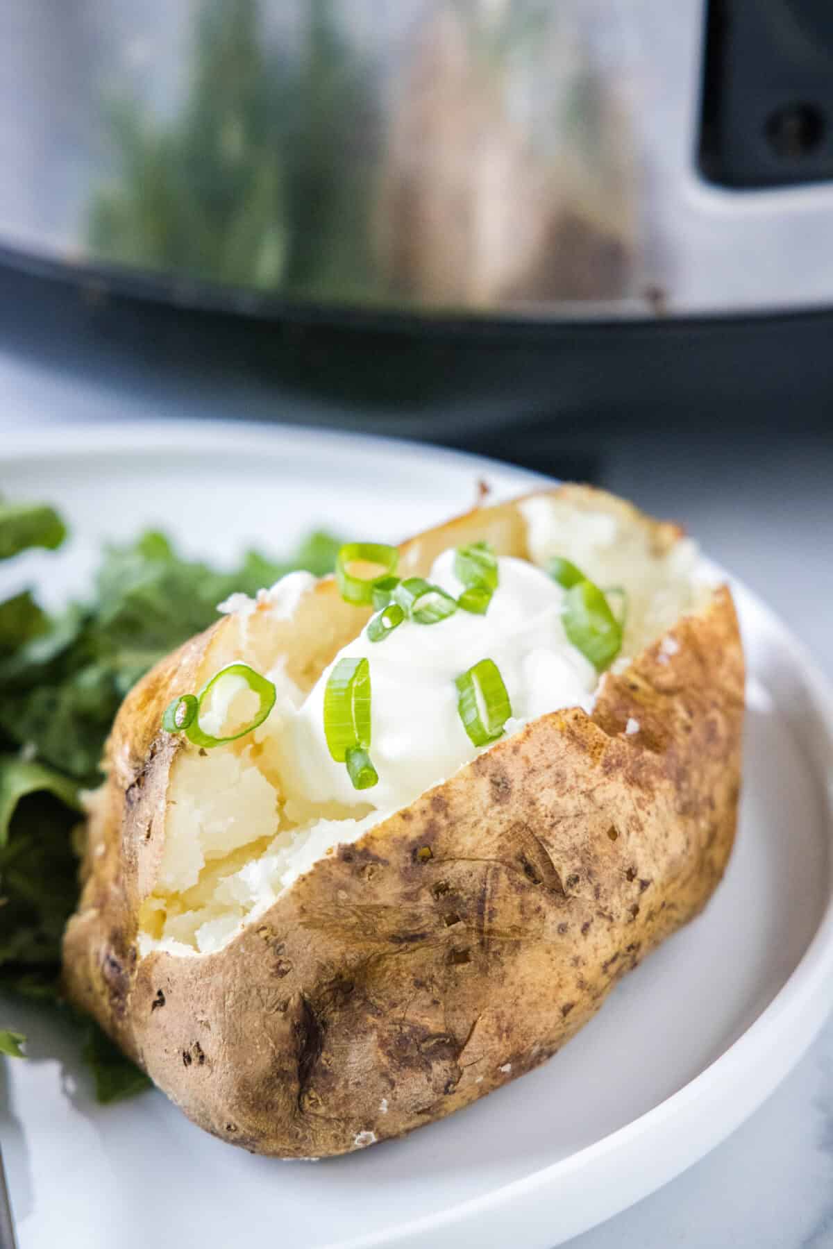 baked potato on a plate topped with sour cream