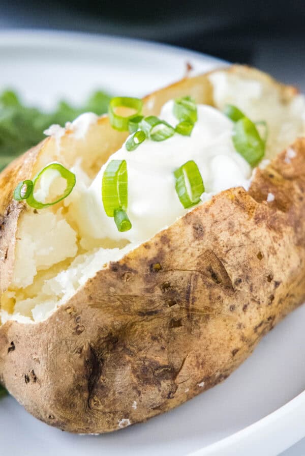 cropped close up slow cooker baked potatoes topped with sour cream