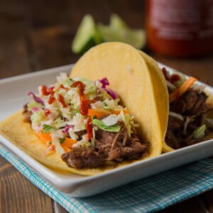 Slow Cooker Korean Beef Tacos - Let your crock pot do the work and get perfectly tender, sweet and spicy beef that is perfect piled on a tortilla topped with a little Korean coleslaw.