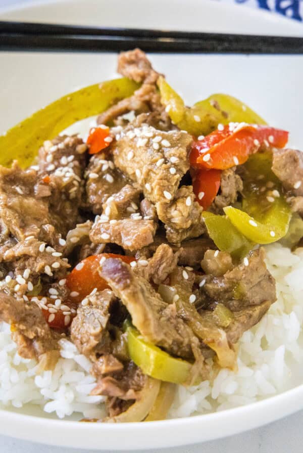 cropped close up pepper steak over rice on a white plate