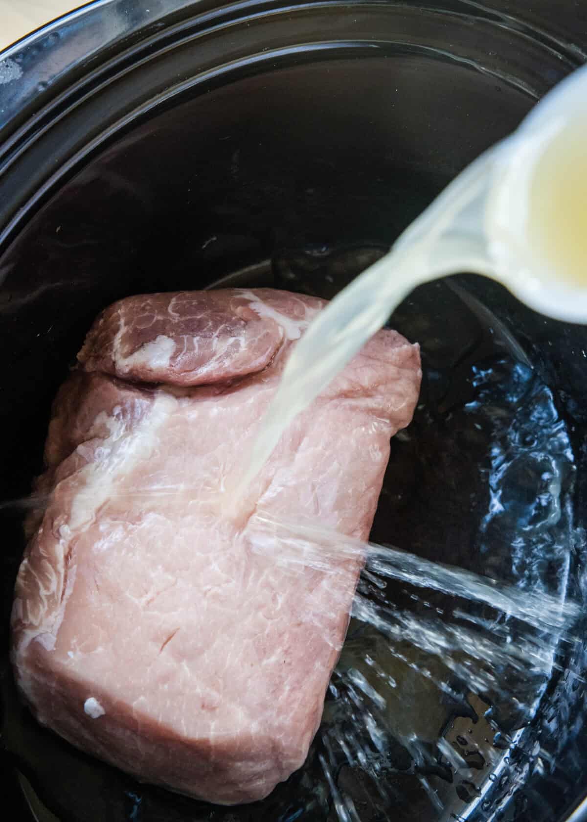 pouring liquid over pork in crockpot