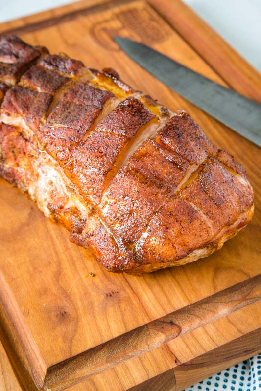 whole pork loin roast on a cutting board with a knife