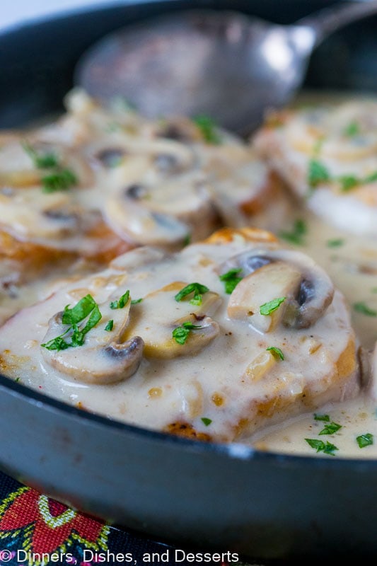 Close up of smothered pork chops with mushroom gravy in a skillet.