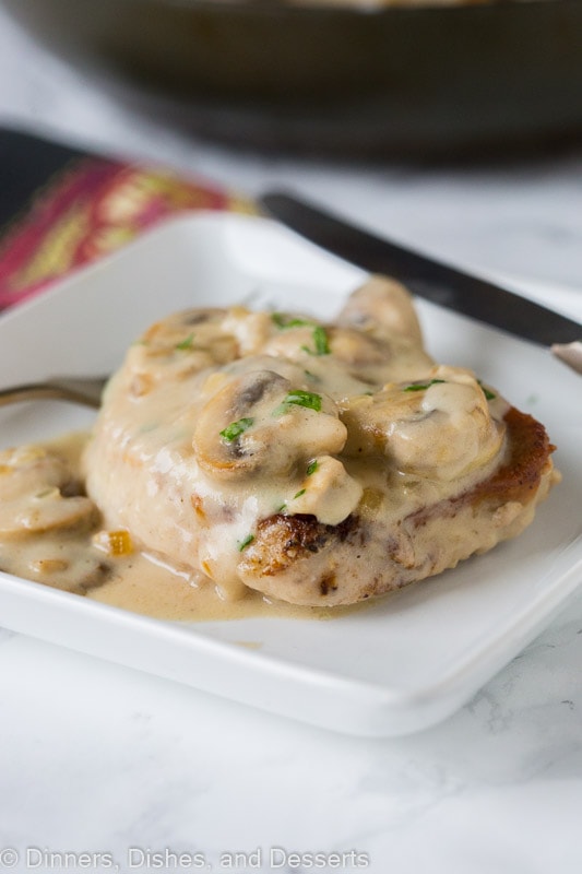 A smothered pork chop topped with mushroom gravy on a plate.