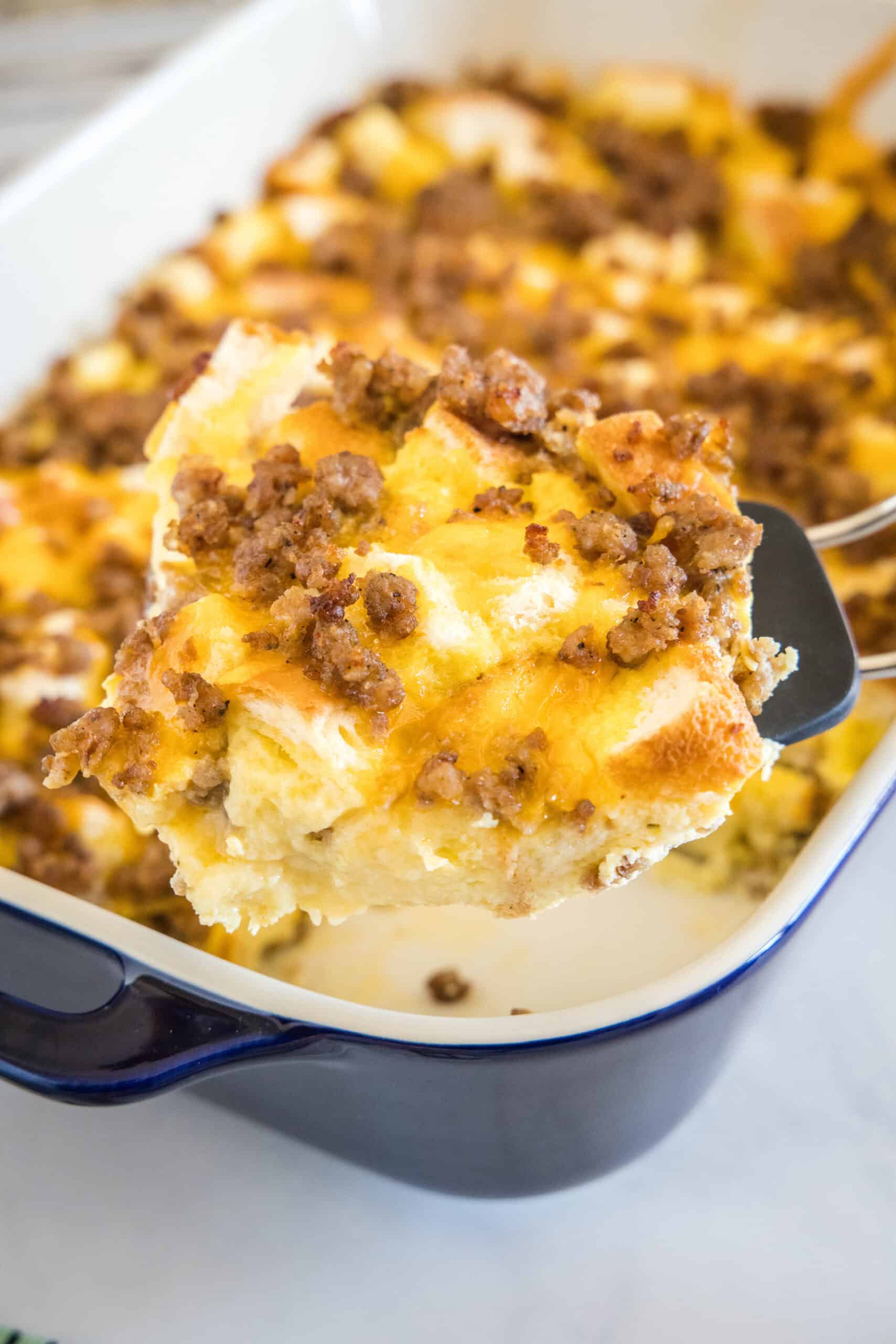 A spatula scooping a serving of sourdough breakfast casserole from a baking dish.