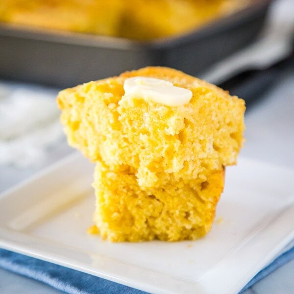 A piece of cornbread with butter on a plate, with Bread and Cornbread