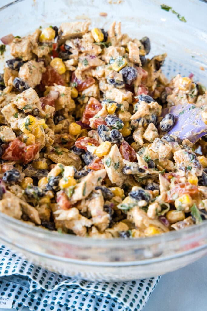 A spatula stirring chicken salad in a bowl