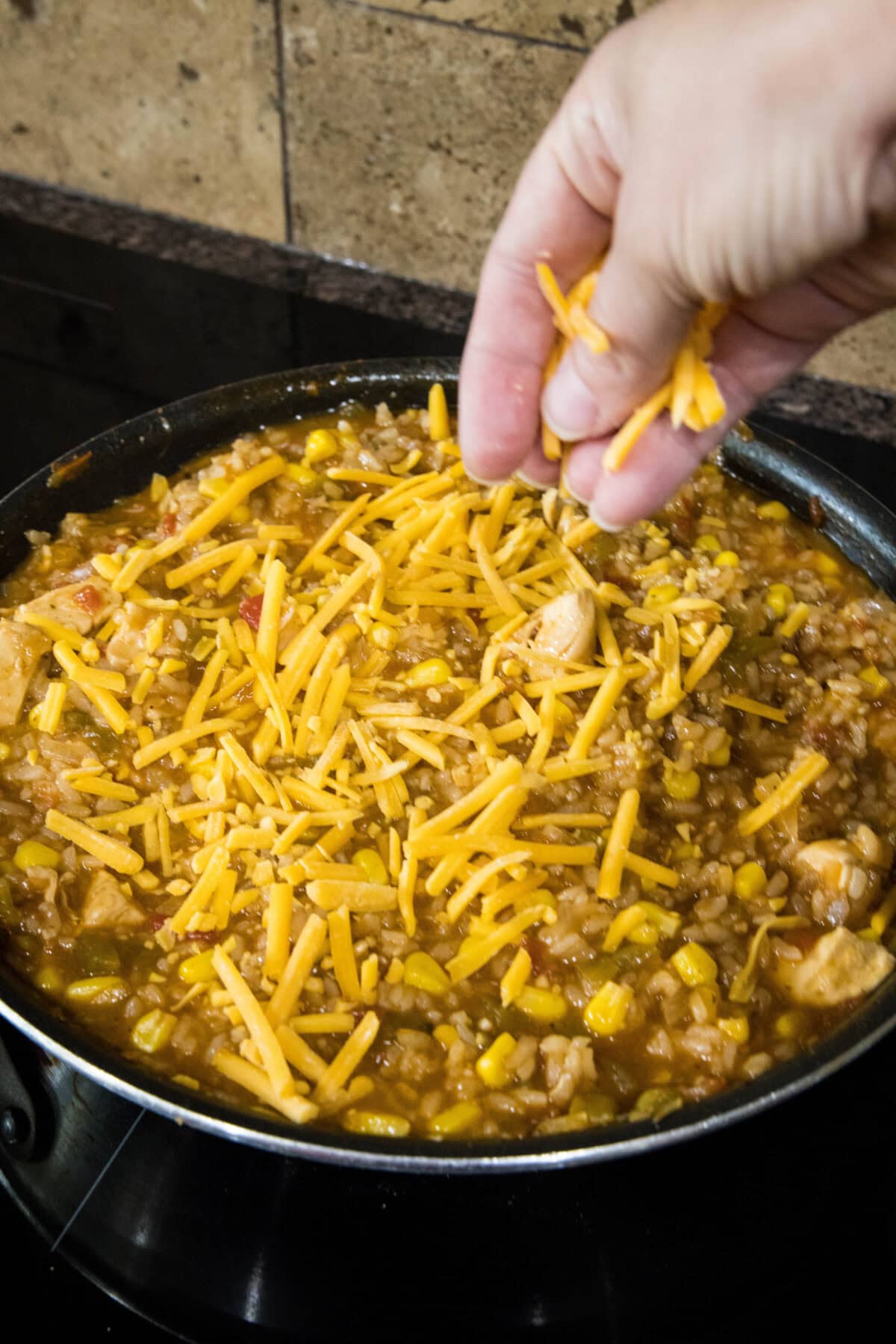 sprinkling cheese over rice skillet