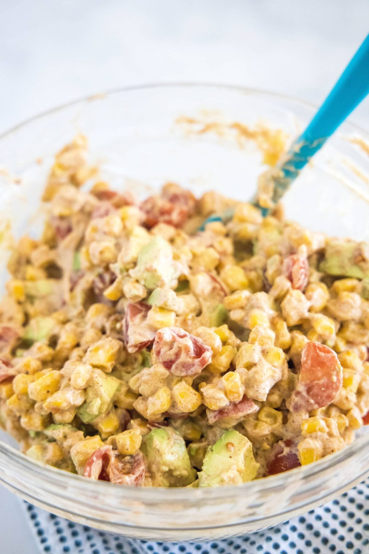 Corn salad in a mixing bowl with a spatula