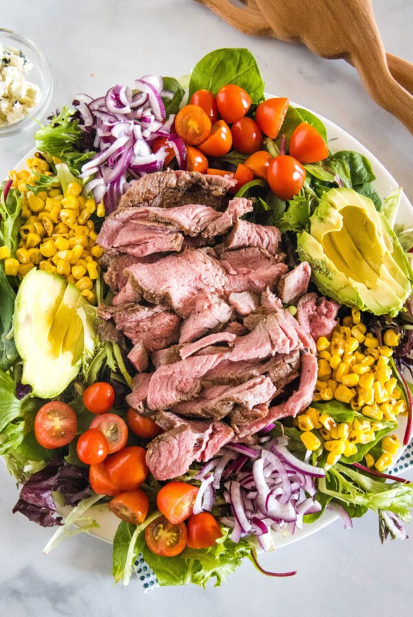 Overhead view of a steak salad on a large platter.