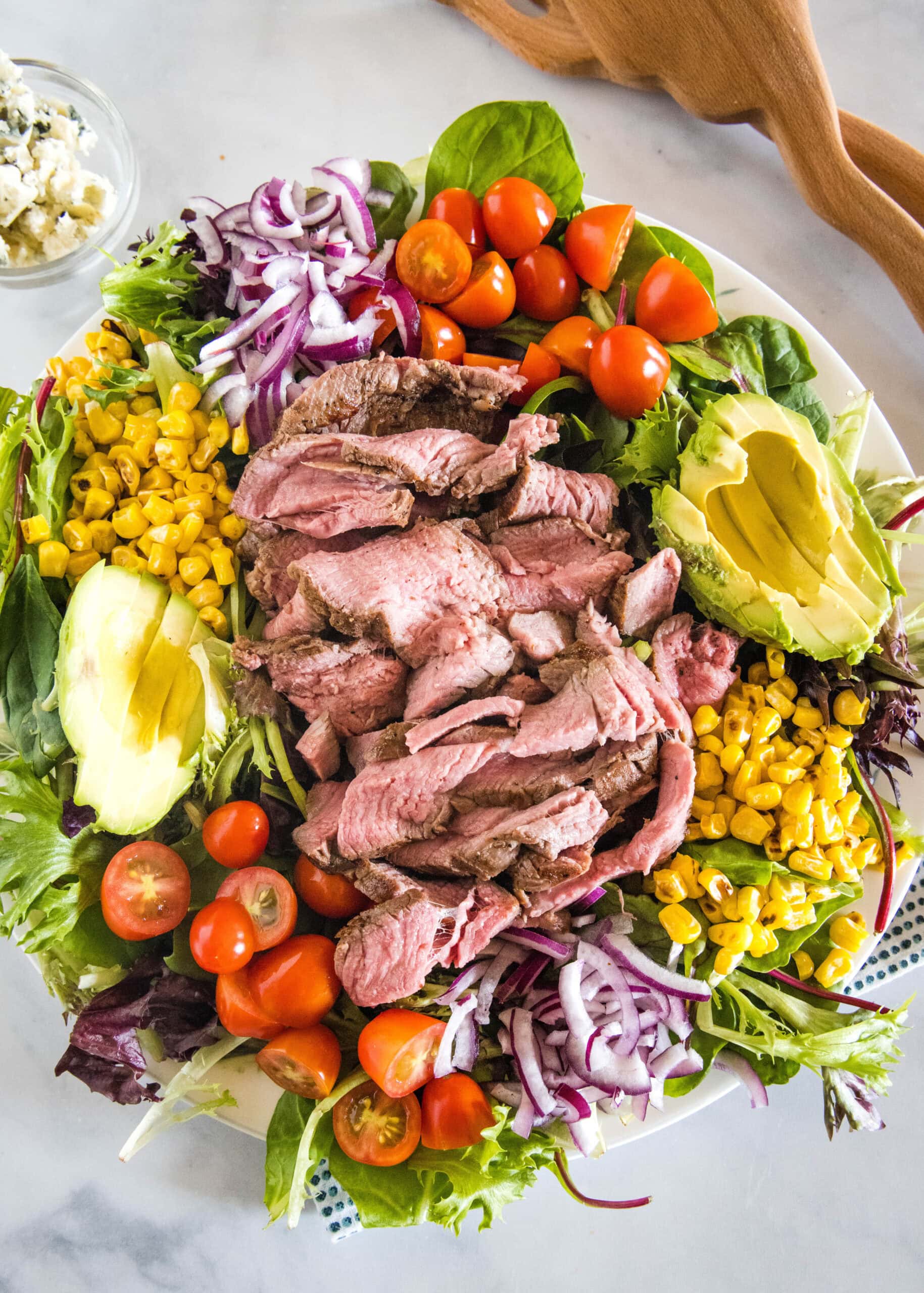 Overhead view of a steak salad on a large platter.