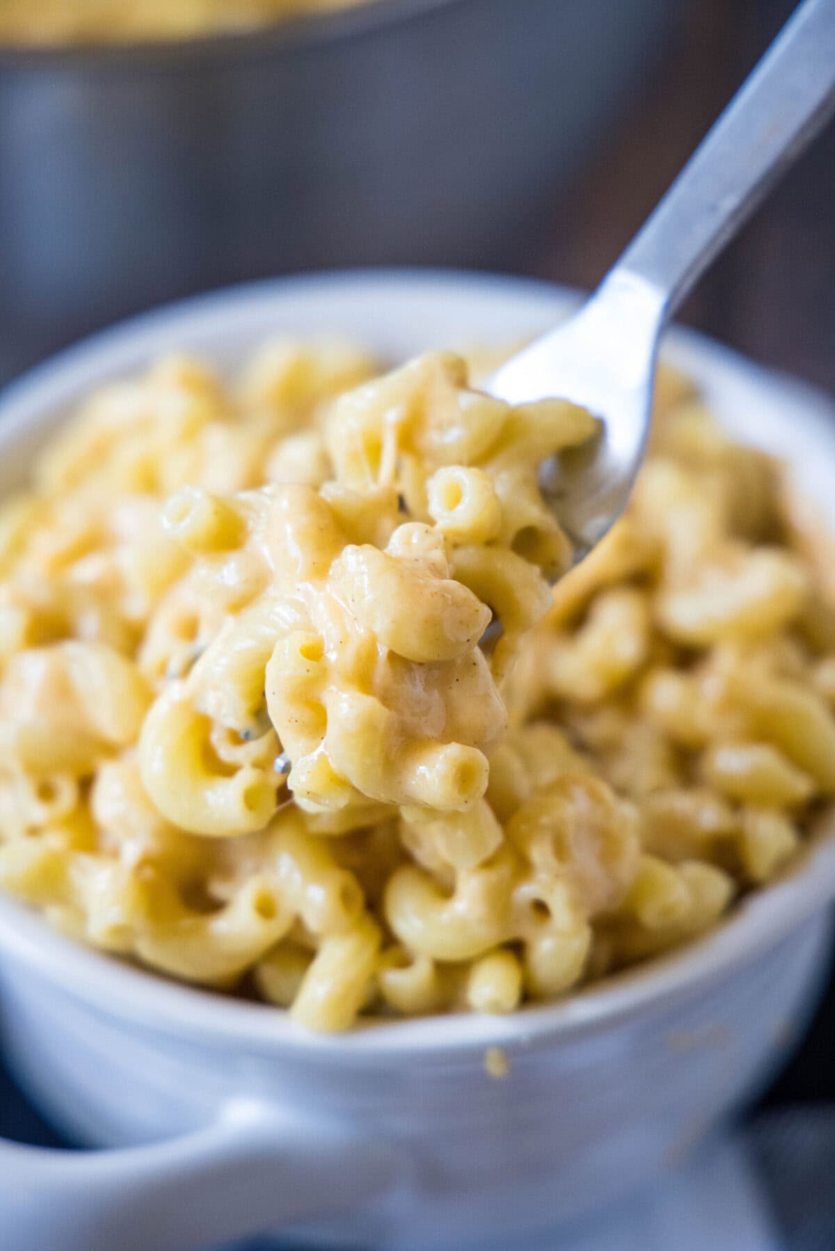 A fork lifting a bite of mac and cheese out of a bowl
