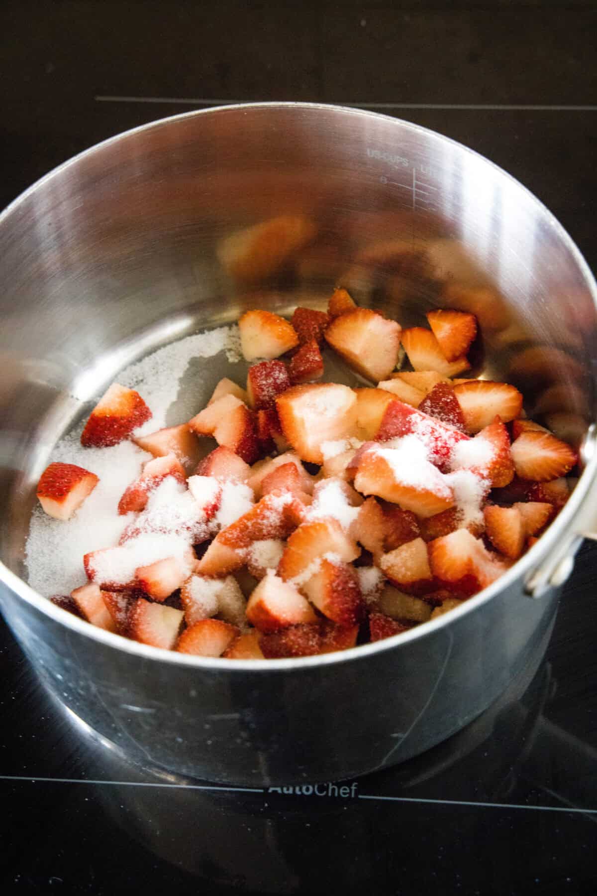 Chopped strawberries and sugar combined in a saucepan.