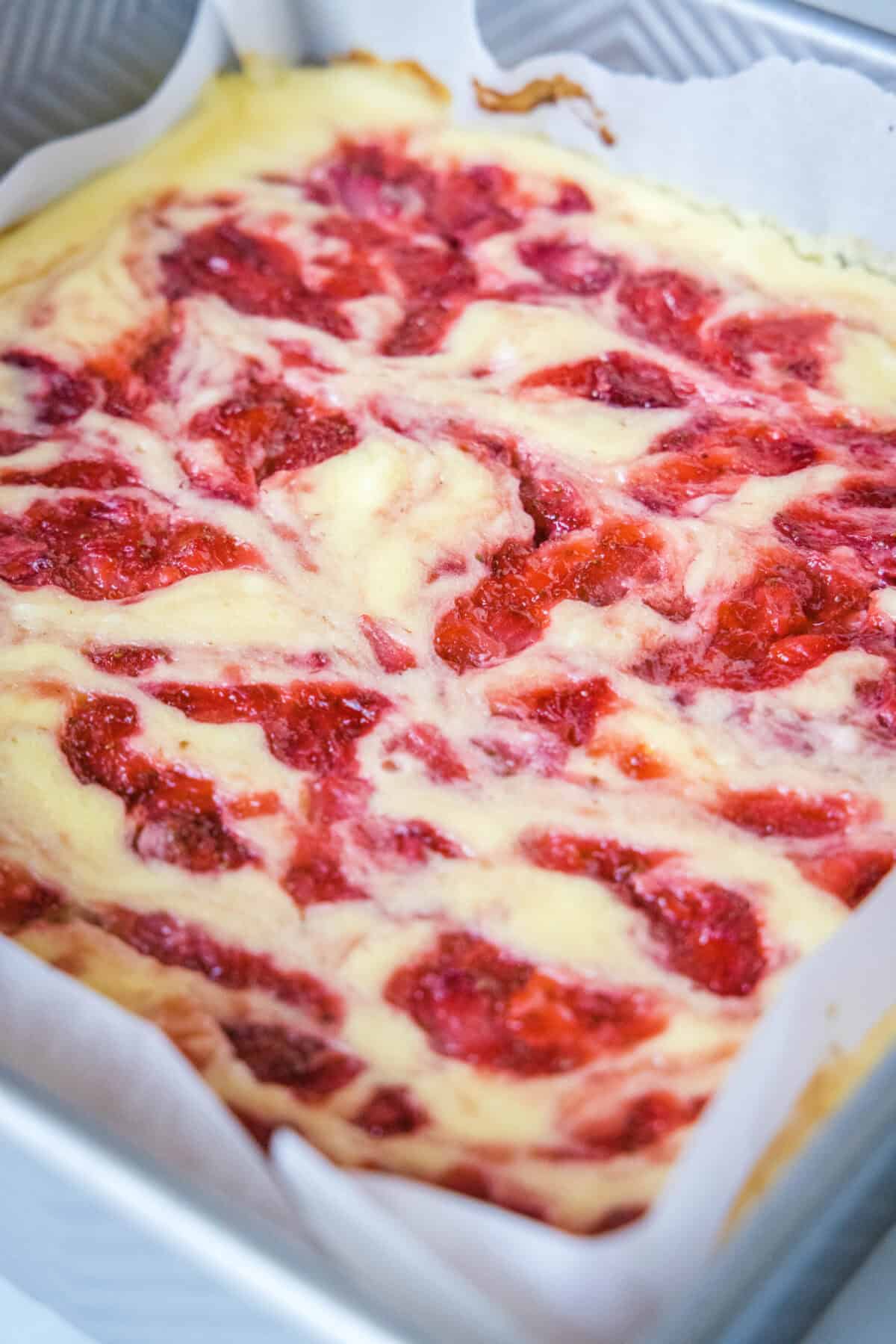 Baked strawberry cheesecake bars in a baking dish.