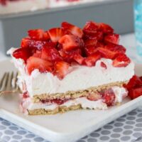 strawberry cheesecake lasagna with fresh strawberries on a plate with a fork