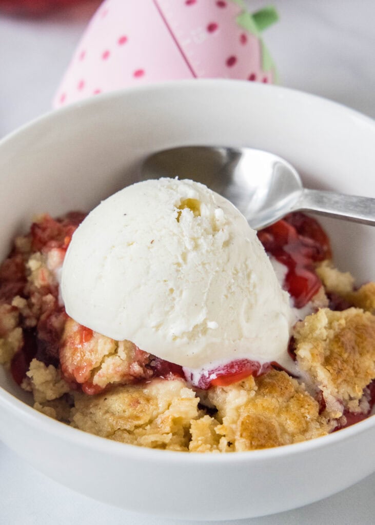 strawberry dump cake in a bowl with ice cream