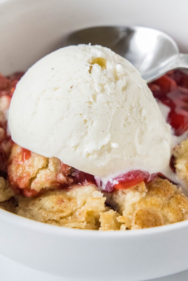 cropped close up strawberry dump cake in a bowl with ice cream